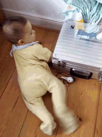 a baby is crawling on the floor next to a briefcase that has the letter s on it