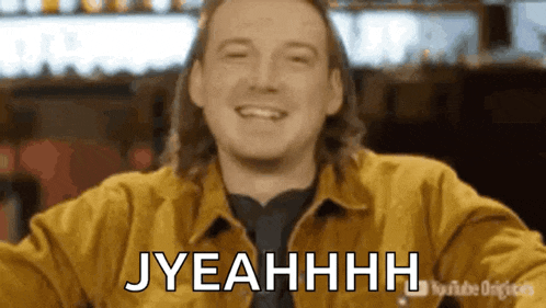 a man in a yellow jacket is smiling and says jyeahhhh .