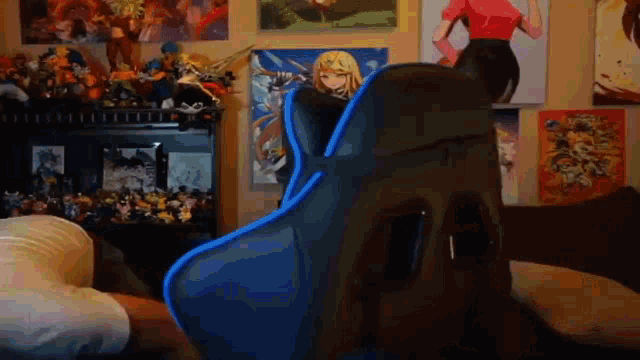 a person is sitting in a blue gaming chair in a room with a lot of posters on the wall .