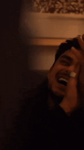 a man with a ring on his finger laughs with his mouth open