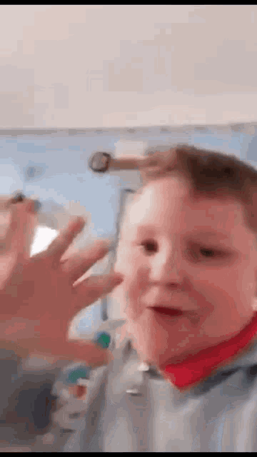 a young boy is making a funny face while waving his hand in a video .