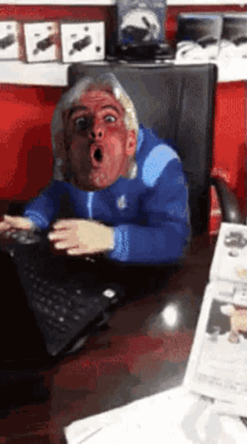 a man in a blue jacket is sitting at a desk with a laptop