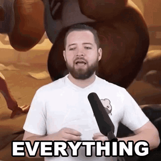 a man with a beard is holding a microphone and saying `` everything '' in front of a cartoon character .
