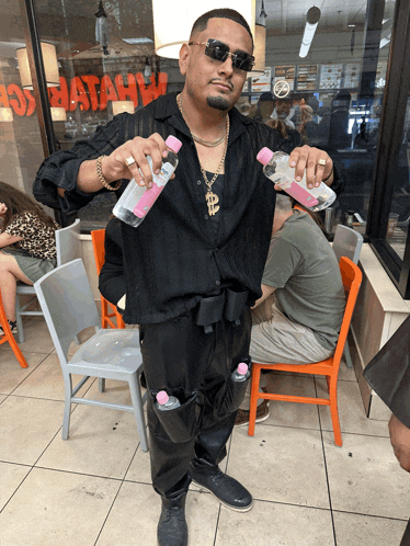 a man wearing sunglasses holds two bottles of water in front of a burger king