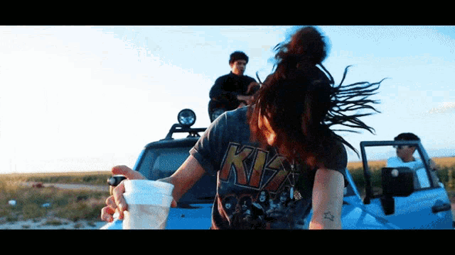 a woman wearing a kiss shirt is holding a cup
