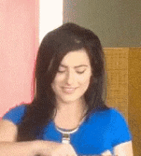 a woman in a blue shirt is smiling and looking at something
