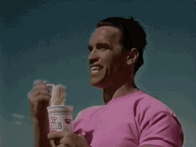 a man in a pink shirt is eating noodles from a cup .