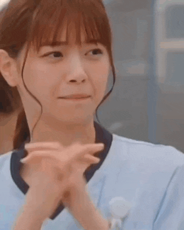 a close up of a woman making a face with her hands folded in front of her face .