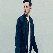 a man in a blue jacket and white shirt is standing in a square