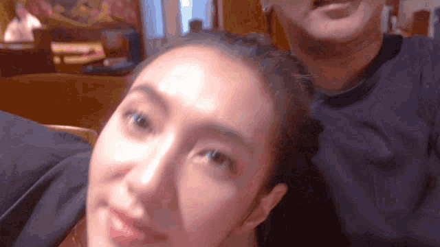 a close up of a woman 's face with a man in the background