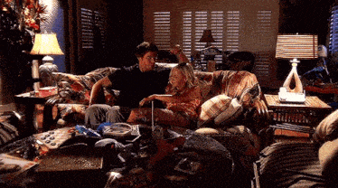 a man and a woman are sitting on a couch in a messy living room .