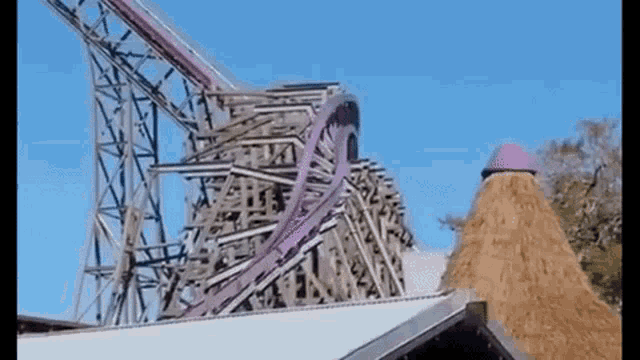 a roller coaster is going down a hill in front of a straw tower .