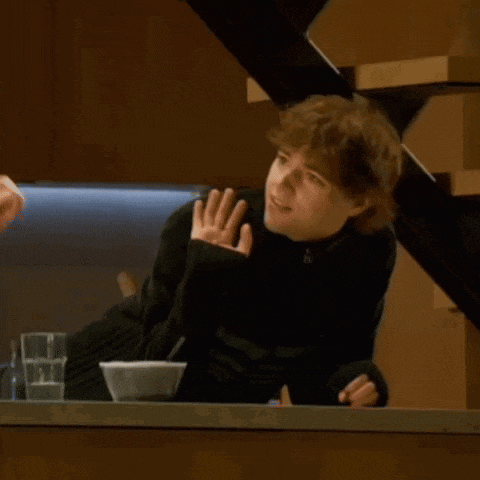 a man in a black sweater is sitting at a counter with a bowl of food
