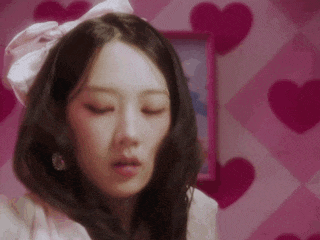 a close up of a woman 's face with her eyes closed in a room with hearts on the wall .