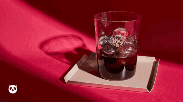 a glass of coffee with milk being poured into it on a tray