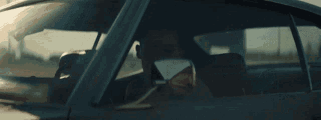 a woman is sitting in the driver 's seat of a car looking out the window .