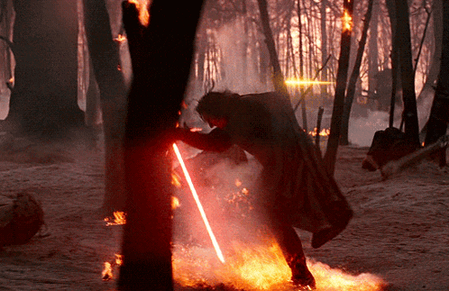 a man is holding a red lightsaber in a forest