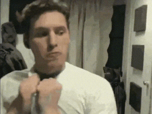 a man in a white shirt is tying a black tie
