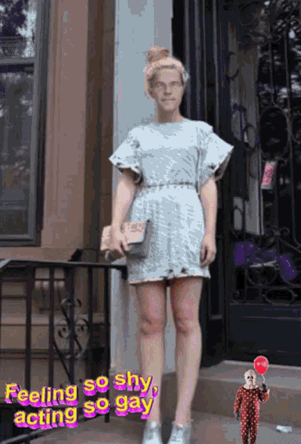 a woman in a dress is standing in front of a building with the words " feeling so shy acting so gay " below her