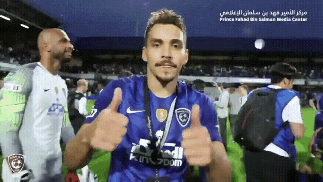 a man in a blue shirt with the word kingdom on it gives a thumbs up