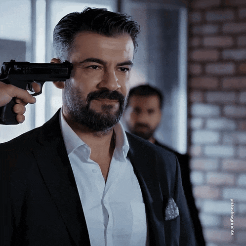 a man with a beard is being shot with a gun by another man