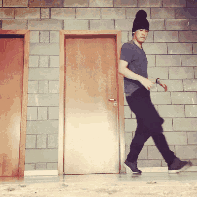 a man wearing a beanie walking in front of a door
