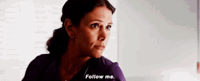 a woman in a purple scrub says " follow me "