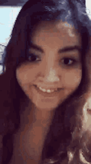 a close up of a woman 's face smiling and looking at the camera .