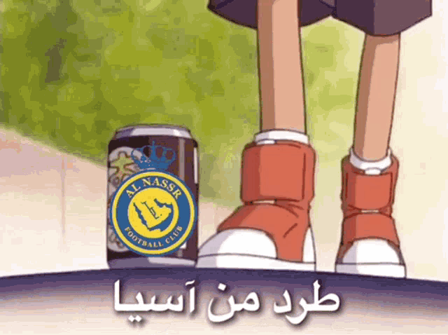 a can of al nassr football club is next to a person 's feet