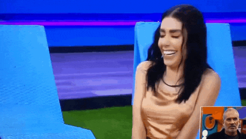 a woman is sitting in a chair on a television show and smiling .