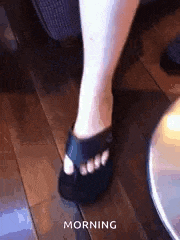 a person is standing on a wooden floor wearing a pair of black crocs .