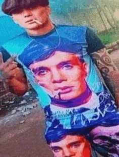 a man is smoking a cigarette while wearing a t-shirt with a picture of a man on it .