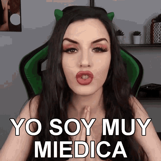 a woman in a green chair with devil horns says yo soy muy medica