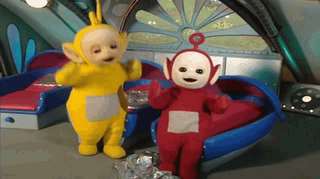 two teletubbies are standing next to each other in front of a couch