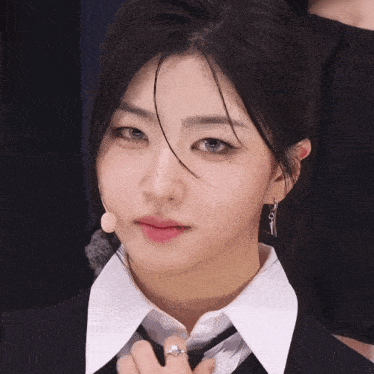 a woman wearing a suit and tie with a microphone in her ear