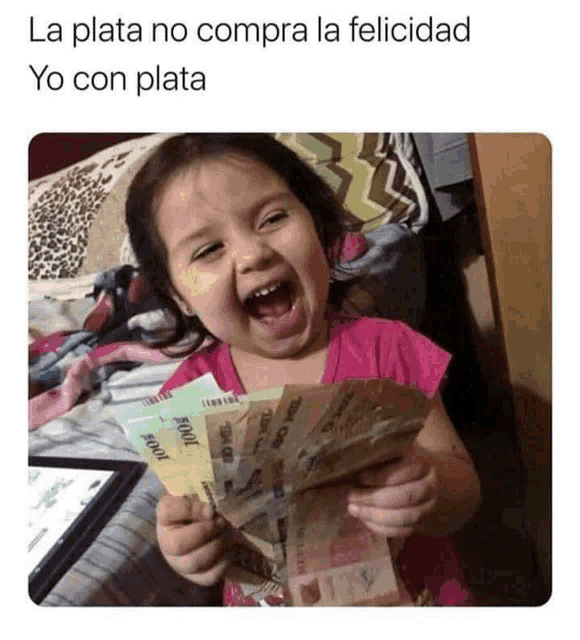 a little girl is holding a bunch of money in her hands and smiling .