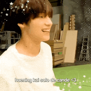 a young man in a white shirt is smiling with the words huening kai solo de cande < 3 below him