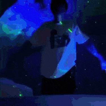 a man in a white shirt is standing in a dark room with a green and red background