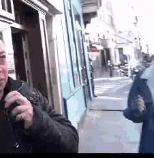 a man is talking on a cell phone while walking down a sidewalk .