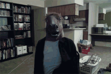 a man wearing a horse mask looks at the camera in a living room