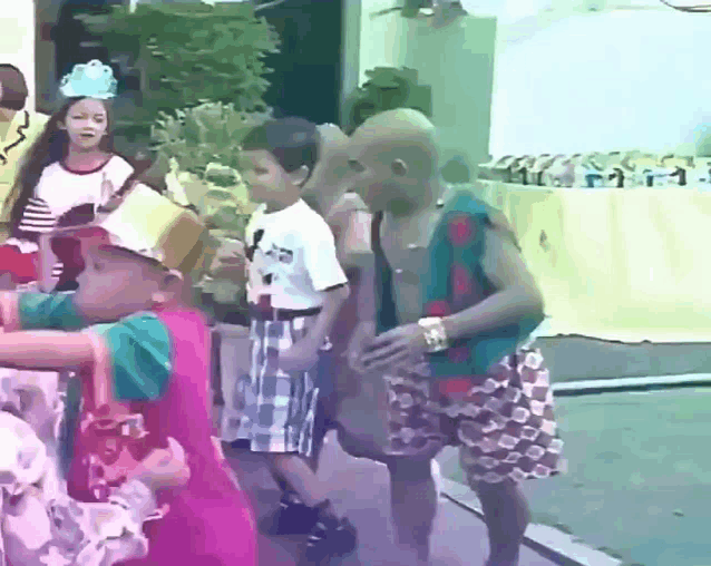 a group of children are walking down a street and one of them has a crown on his head