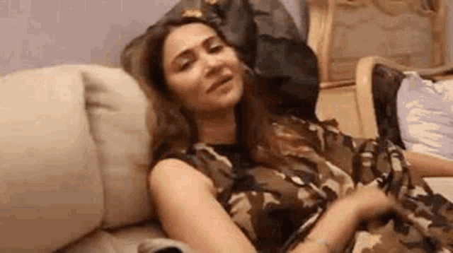 a woman is laying on a couch with her head on a pillow and smiling .
