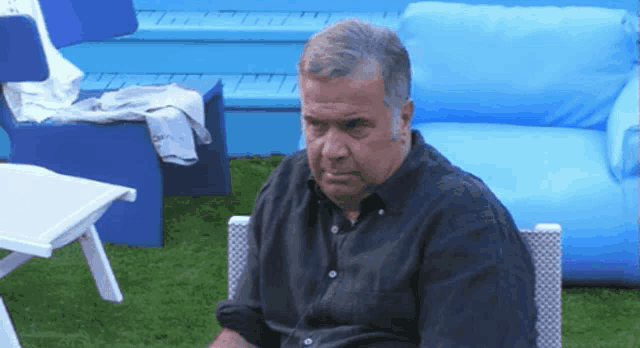 a man in a black shirt sits in a chair on the grass