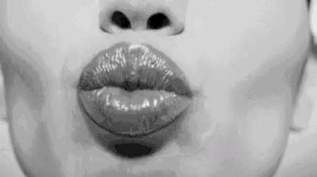 a close up of a woman 's lips blowing a kiss .