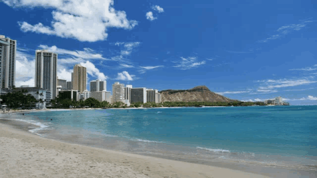 a beach with a mountain in the background and buildings in the background