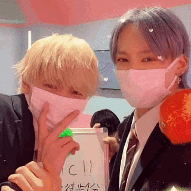 two people wearing face masks are posing for a picture with a sign that says " ici "