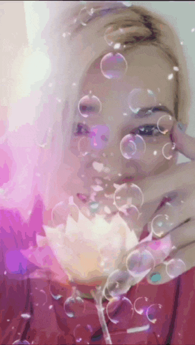 a woman blowing soap bubbles in front of her face