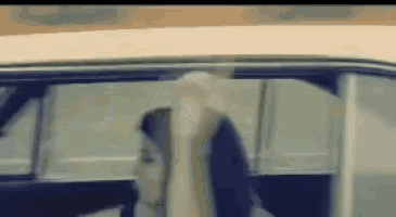 a woman is sitting in the driver 's seat of a car with her arms outstretched .