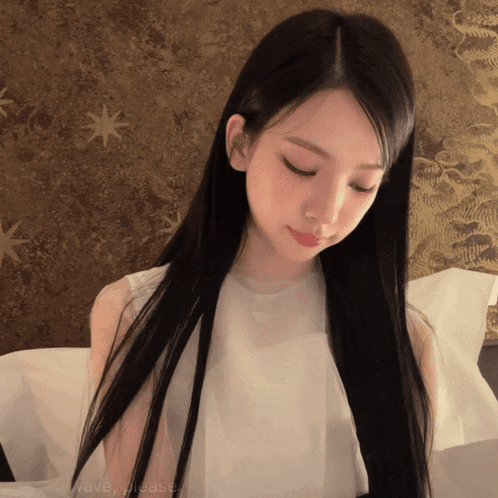 a woman with long black hair is sitting on a bed with the words wave please written on the bottom