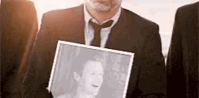 a man in a suit and tie is holding a picture of a man in a frame .